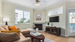Ein Wohnzimmer mit Kamin, einer Couch, einem Couchtisch und einem an der Wand montierten Fernseher.