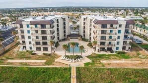 Un moderno complejo de apartamentos con varias construcciones, un patio central con piscina y zonas verdes circundantes.