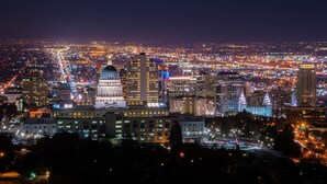 A cityscape at night with illuminated buildings and a prominent dome structure.