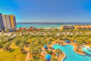 Relax by the pool surrounded by lush greenery and palm trees, with lounge chairs and umbrellas for comfort.