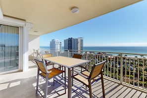 Enjoy the ocean view from this balcony with a table and chairs.