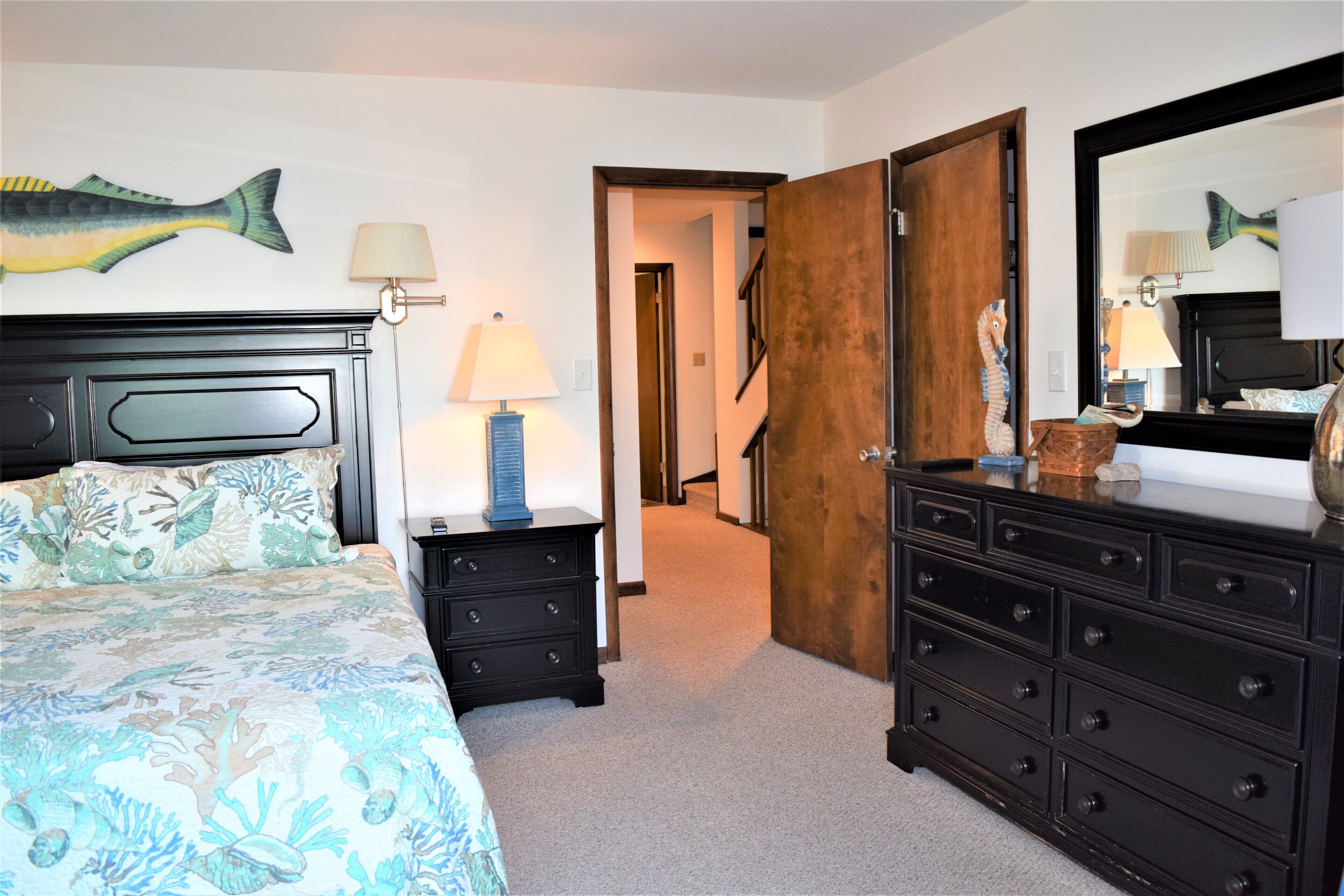 Une chambre à coucher comprenant un lit, des tables de chevet, une commode et un miroir.