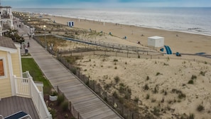 Une plage avec une promenade en bois menant à une zone sablonneuse, un poste de surveillance pour les sauveteurs et une vue dégagée sur l’océan.