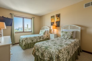 Une chambre d’hôtel avec deux lits simples, une télévision, un bureau et une fenêtre donnant sur la ville.