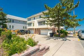 Un immeuble résidentiel de deux étages avec un garage, des voitures garées et un arbre dans l’allée.