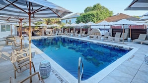Zona de piscina con sillas de descanso, sombrillas y un cartel que indica prohibido bucear.