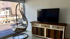 Ett rum med en hängstol, en tv placerad på ett träskåp och utsikt över omgivningen.