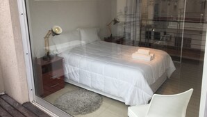 Ett sovrum med en säng, sängbord, en lampa och en stol.