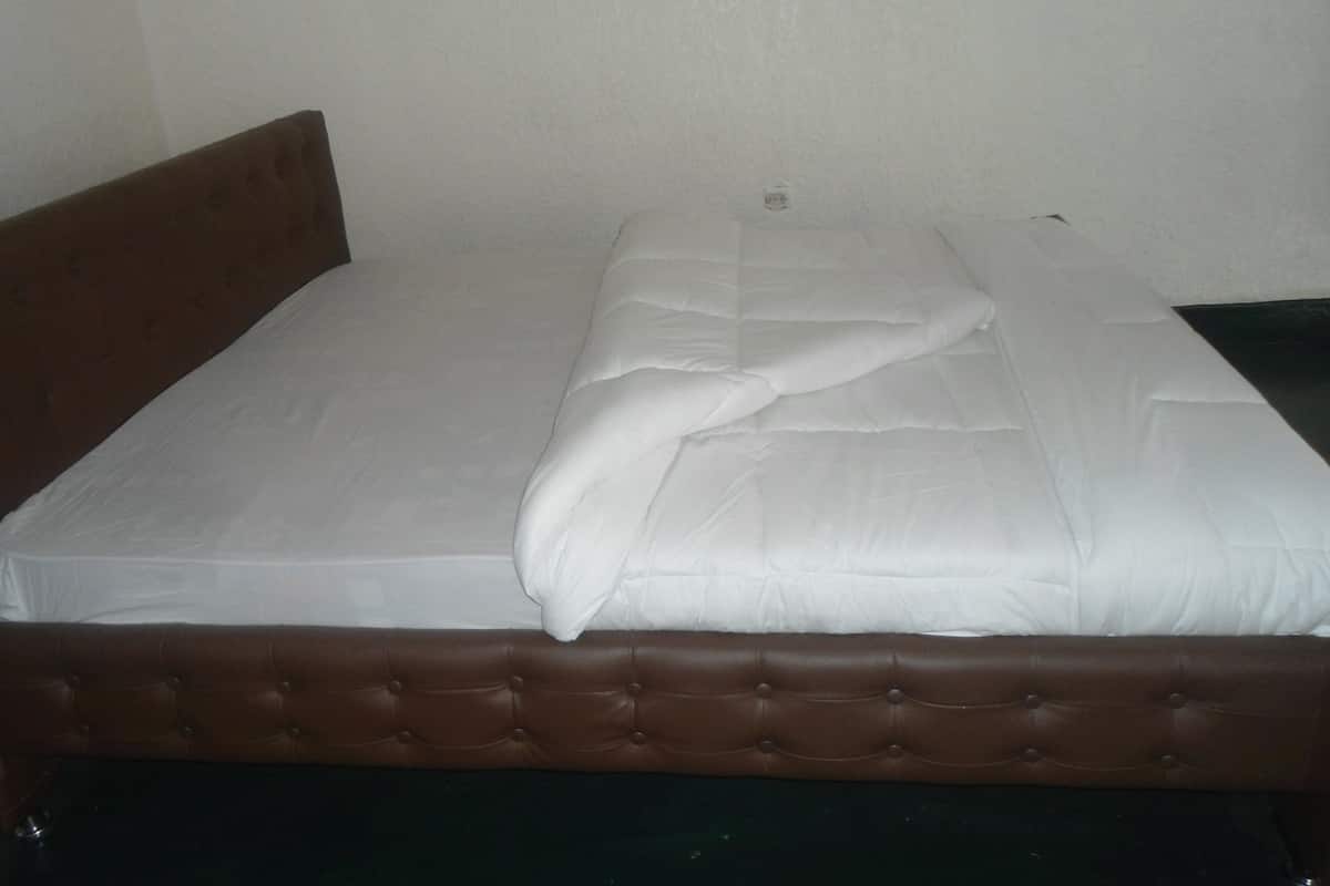 A single bed with a brown headboard and white bedding.