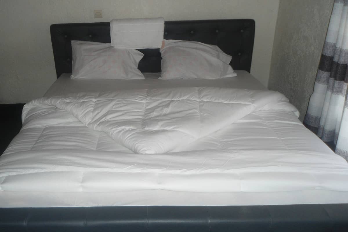 A bed with white bedding and a dark headboard.