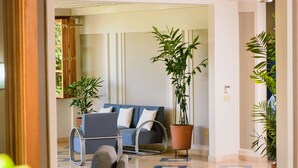 En moderne hotellobby med en sofa, stole og potteplanter.