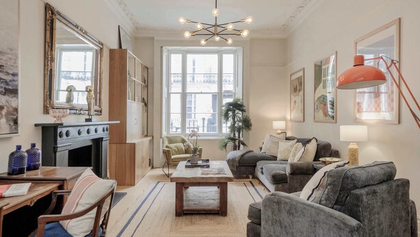A living room with a fireplace, sofa, coffee table, and a dining area with chairs and a table. - 2-bed flat in Paddington - Hyde Park (Greater London)