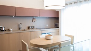 A modern kitchen with a round dining table, light-colored cabinets, and a hanging light fixture.