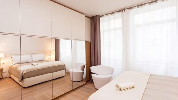 A modern hotel room with a large bed, a seating area, and a large mirror.