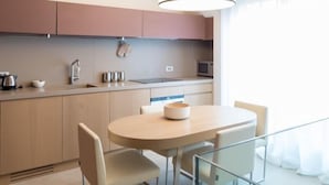 A modern kitchen with a round dining table, two chairs, and a glass railing.