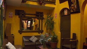 Una sala de estar acogedora con un sofá de cuero marrón, una mesita con un florero y una planta en maceta.
