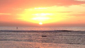 Un coucher de soleil sur l’océan, avec un bateau à l’horizon.