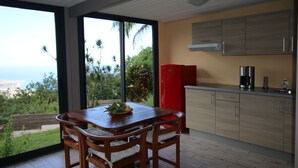 Une cuisine moderne avec des meubles en bois, un réfrigérateur rouge et un coin repas comprenant une table et des chaises en bois.