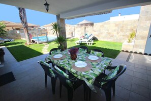 An outdoor patio with a table set for four, surrounded by chairs, and a pool in the background. - Private Pool, ideal family holidays, beautiful garden, WiFi internet and aircondition- Casa Ivan - (Conil de la Frontera)
