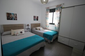 A bedroom with two beds, a wardrobe, and a window with curtains. - Private Pool, ideal family holidays, beautiful garden, WiFi internet and aircondition- Casa Ivan - (Conil de la Frontera)