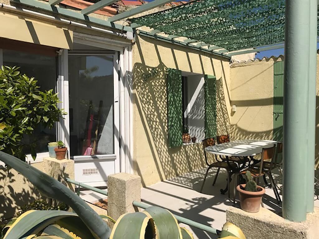 A patio area with a table and chairs, a door, and potted plants.