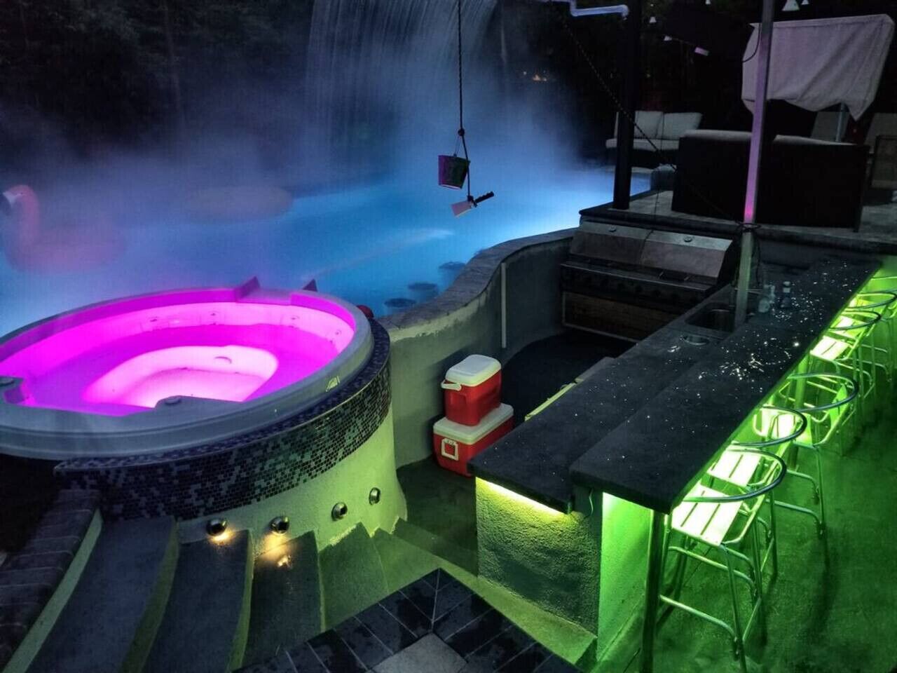 Een bubbelbad met een waterval op de achtergrond, een bar met krukken, en een klein zitgedeelte.