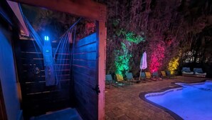 A spa area with a hot tub, a wooden door, and a brick patio with lounge chairs. - Private Luxury Pool / Swim up bar / Smart-home (Orlando)