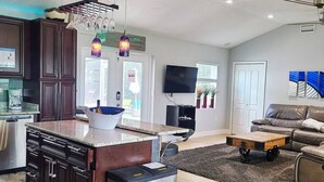 A modern kitchen with dark cabinetry, a stainless steel refrigerator, and pendant lighting. - Private Luxury Pool / Swim up bar / Smart-home (Orlando)