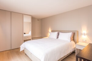 Een moderne hotelkamer met een groot bed, een kledingkast en bedlampen.