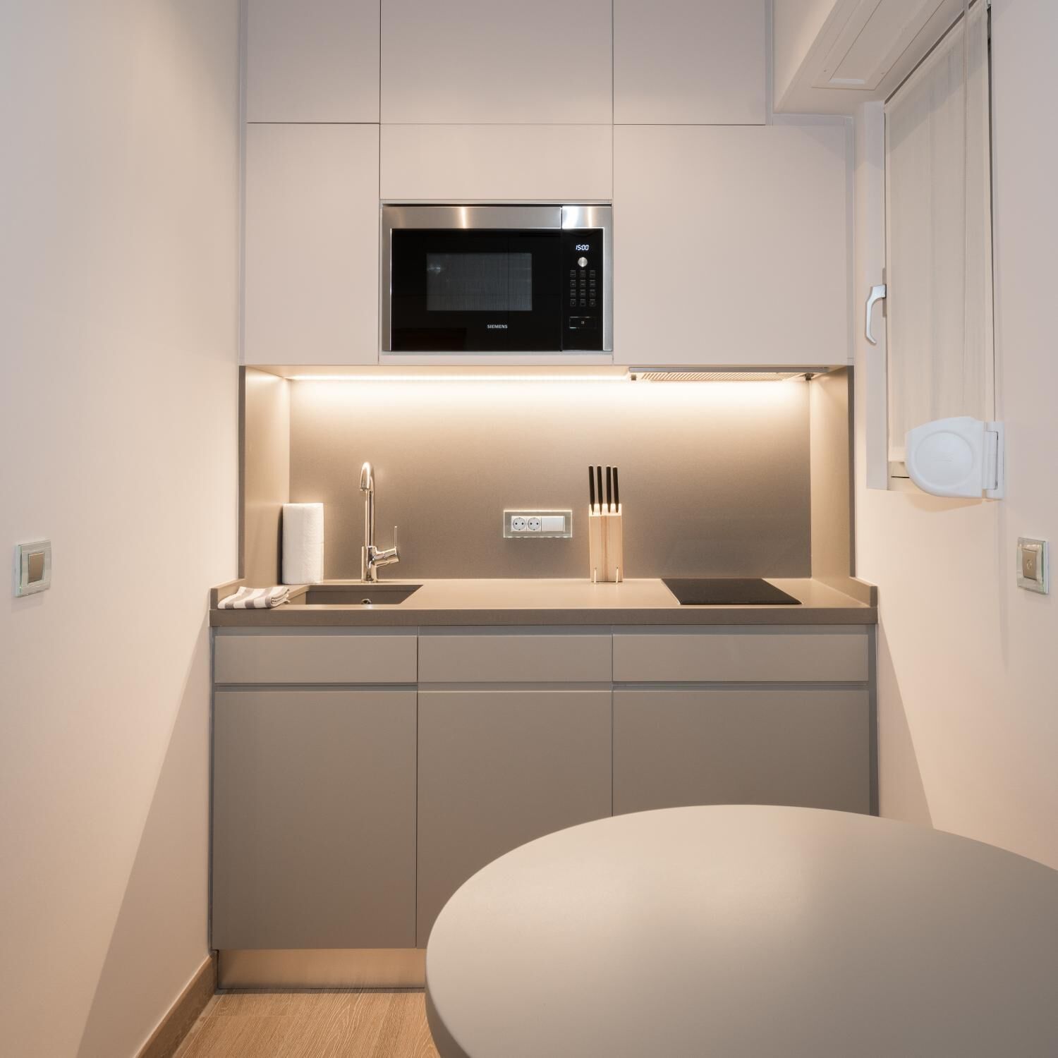 A compact kitchen with a built-in microwave, a sink, and a small countertop.
