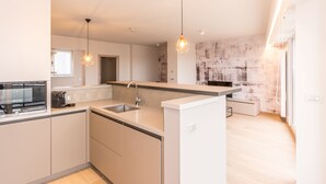 Une cuisine moderne dotée d’un îlot central, d’un four encastré et de luminaires suspendus.