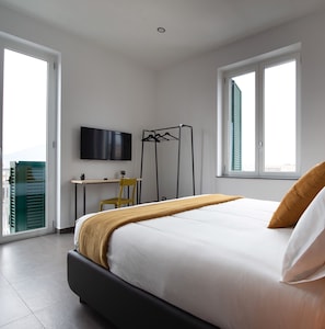 A bedroom with a bed, a desk, a chair, a TV, and a window. - GB Vesuvius Napoli (Naples)