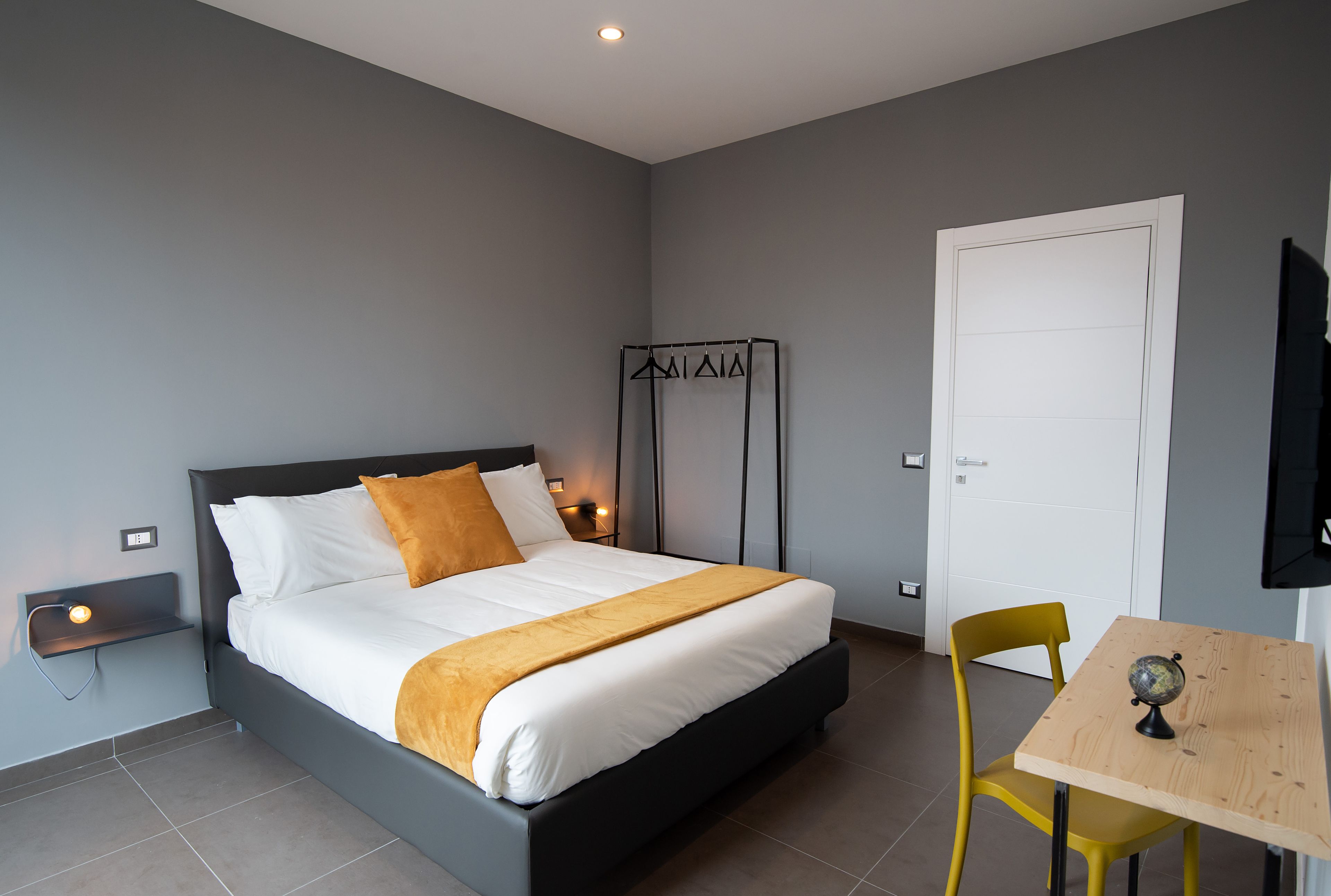 Une chambre à coucher moderne avec un lit, des tables de chevet, un bureau et une chaise.