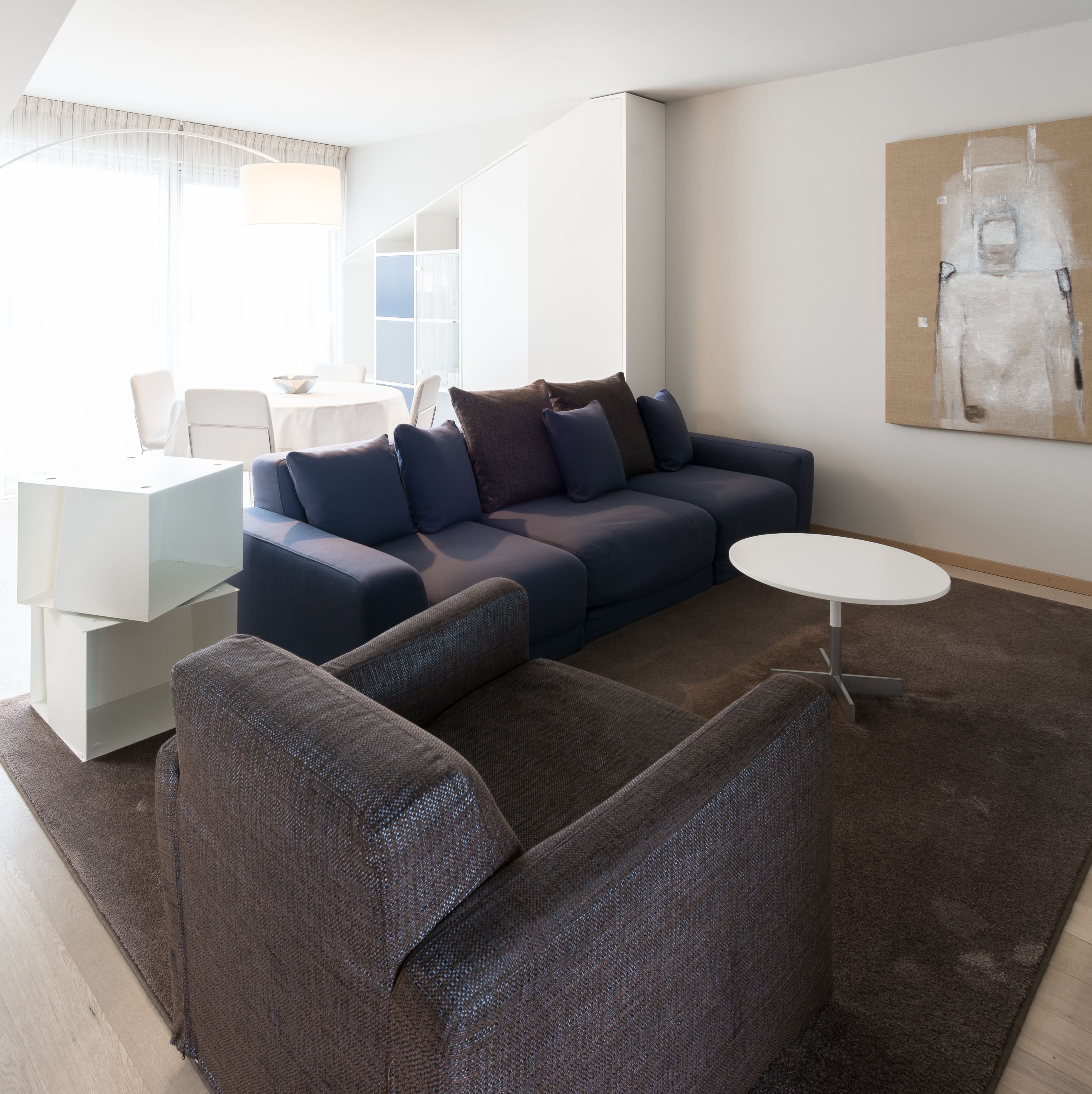 A modern living room with a sofa, a coffee table, and a dining area with a table and chairs.