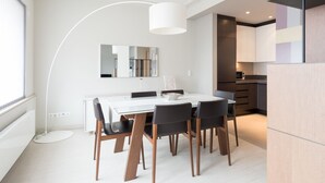 A modern dining area with a white table and chairs, a large mirror, and a pendant light. - Four Stars Aparthotel (Luxembourg City)