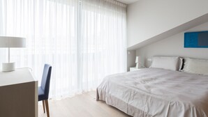 A modern bedroom with a large bed, a desk, and a chair. - Four Stars Aparthotel (Luxembourg City)