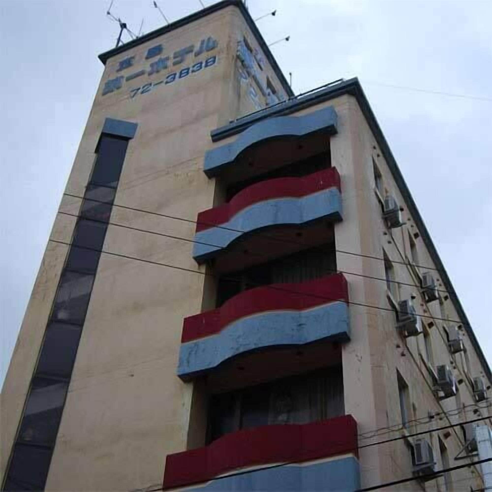 A tall building with multiple balconies, a visible phone number, and a sign with Japanese characters.