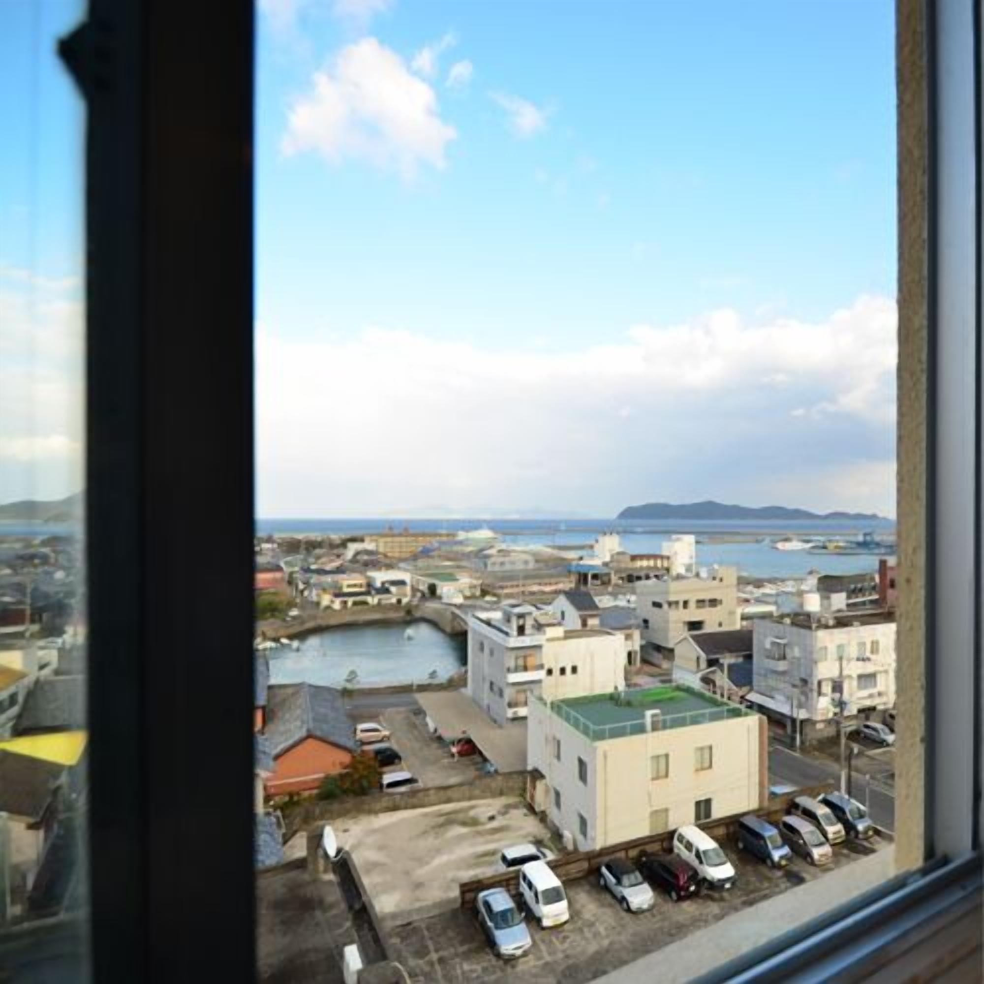 A coastal cityscape with buildings, a body of water, and a clear sky.