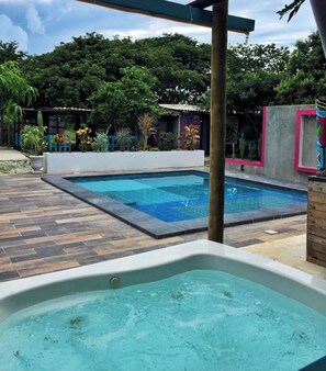 A swimming pool area with a hot tub, surrounded by a wooden deck and lush greenery. - Paraiso Lounge Santa Marta (Santa Marta)