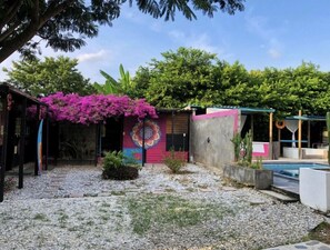 Ein Innenhof mit Pool, Wandgemälde in leuchtenden Farben und einer Pergola mit lila Blumen.