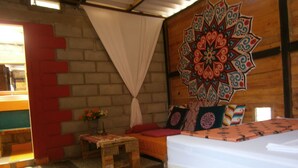 A room with a bed, a small table with a vase of flowers, a wall with a colorful geometric pattern, and a red and white striped wall. - Paraiso Lounge Santa Marta (Santa Marta)