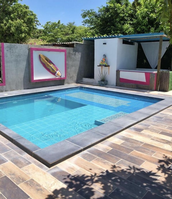 Ein rechteckiger Pool mit einer gefliesten Kante, umgeben von einer Holzterrasse.