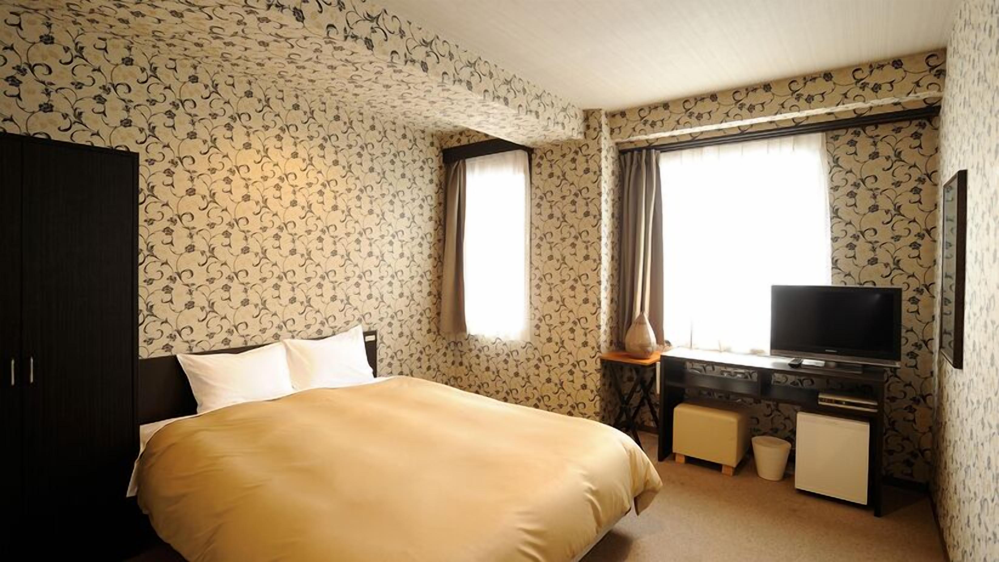 Una habitación de hotel con cama, televisión, escritorio y ventana.