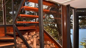 Een modern interieur met een houten trap, een metalen leuning en uitzicht op een meer.
