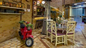 A cozy indoor setting with a brick wall, a scooter with a basket, and a bar area with stools and a counter.