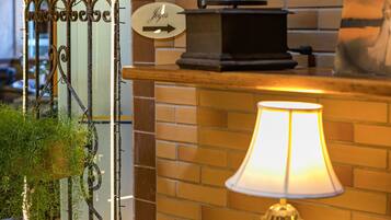 A vintage radio, a clock, and a lamp on a wooden counter against a brick wall.