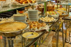 Buffet com diversos alimentos, incluindo tortas, doces e pão.