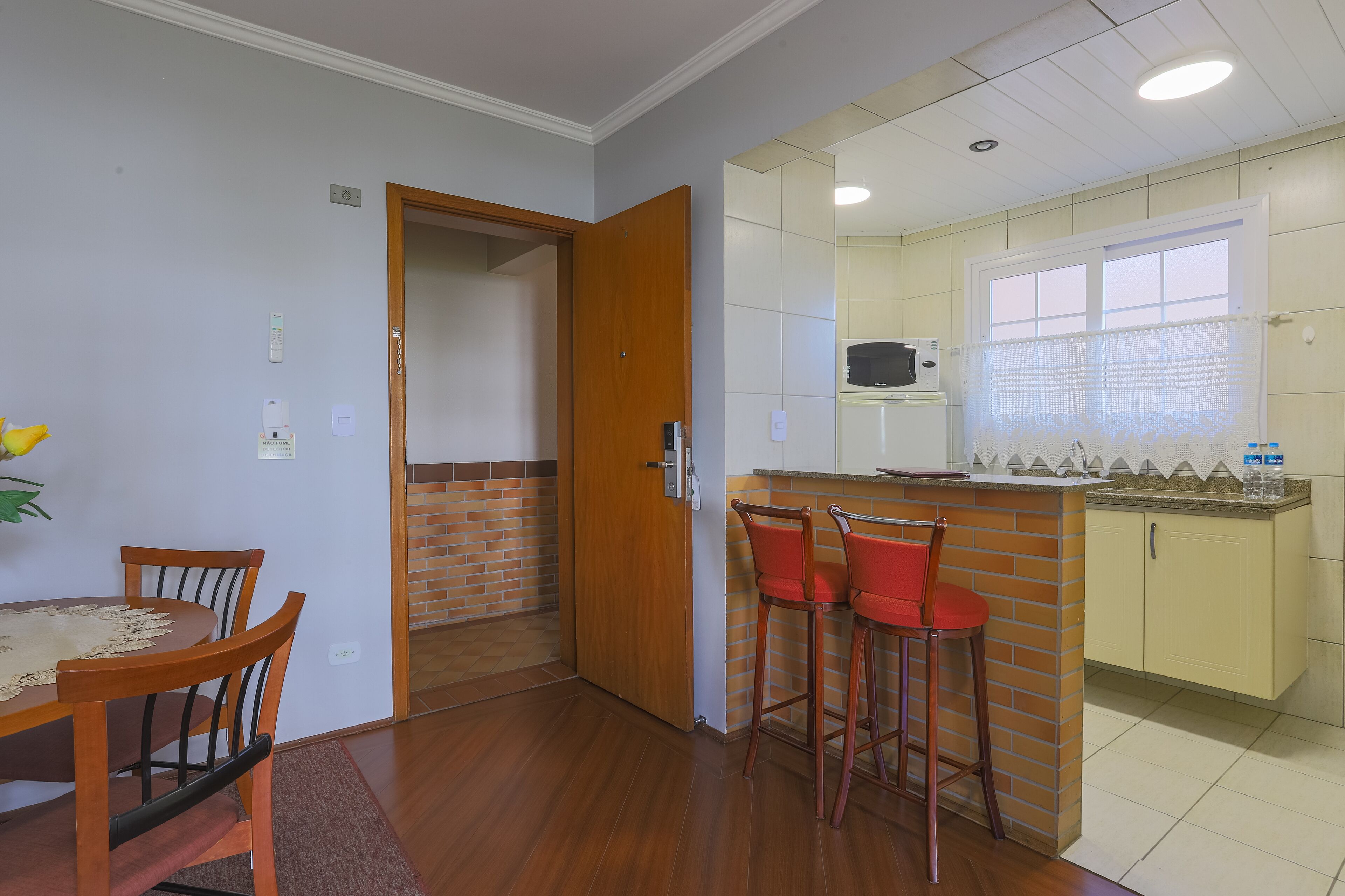 A compact kitchen with a wooden dining table and chairs, a small bar area with stools, and a visible microwave.
