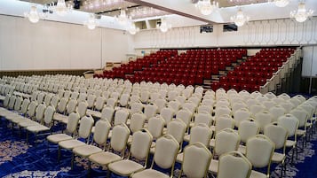 A conference room with rows of white chairs and red seating in the back.