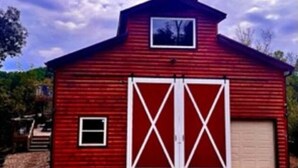 A red barn with two large white doors and a small window on the front.